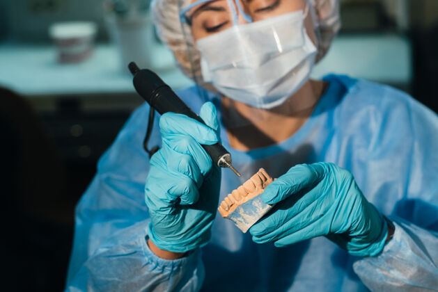 牙齿一个戴着面罩的牙科技师在他的实验室里做假牙医药龋齿办公室