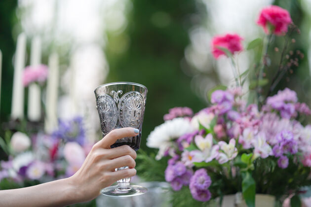 阳光明媚的早晨女人手里拿着一杯水花园和鲜花背景新鲜女人杯子