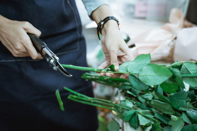 准备特写花店女手剪花茎在花店工作自然商业场景