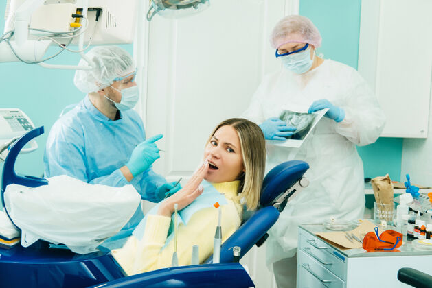 讨论牙医向他的同事解释x光片的细节 病人对所发生的事情感到惊讶制服人牙齿