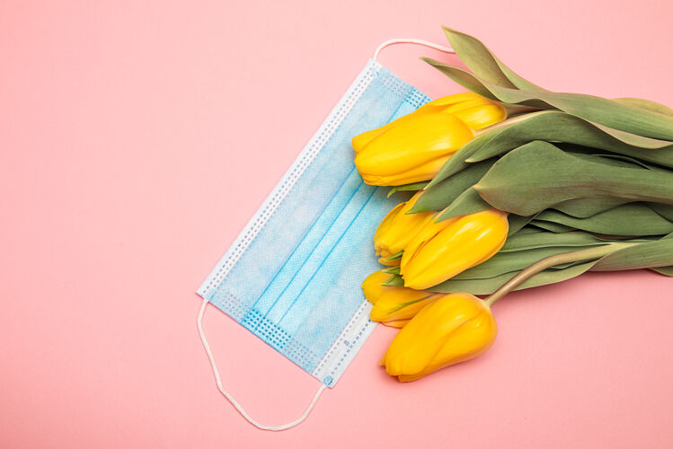 花朵蓝色的医学面具和黄色的郁金香在粉红色的背景下 感谢医生的概念合影复活节护理面罩