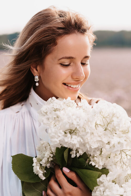 头发夏日田野里 一位身着白色连衣裙 手持一束鲜花的美丽女孩的画像美丽开花肖像