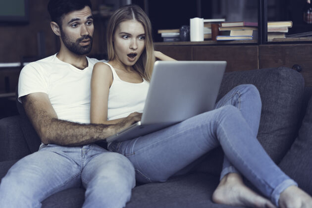 情人节一对在沙发上使用笔记本电脑的幸福夫妻娱乐聊天休息
