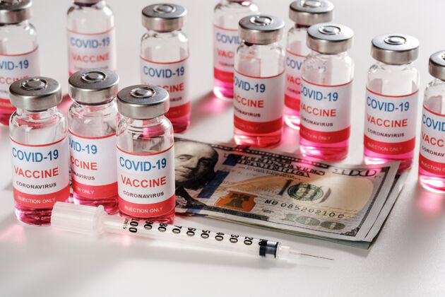 钱新的冠状病毒感染疫苗与美元纸币和注射器上的白色昂贵的小瓶注射器