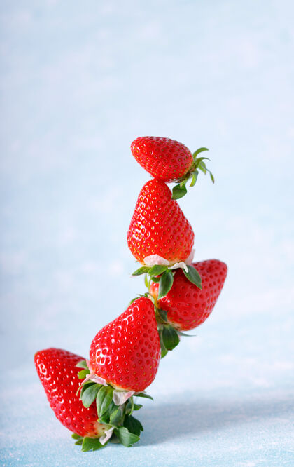 夏天生的红色有机草莓在蓝色的背景上一串美丽营养种子