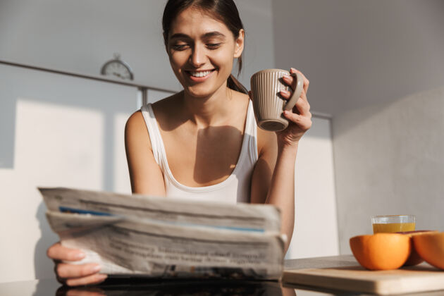 拿铁微笑的年轻女孩早上站在厨房 看报纸 喝茶美味咖啡室内