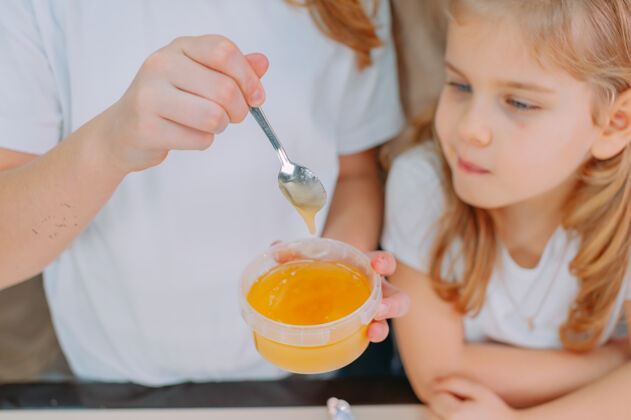 童年两姐妹用茶匙尝甜甜的蜂蜜在一起人孩子