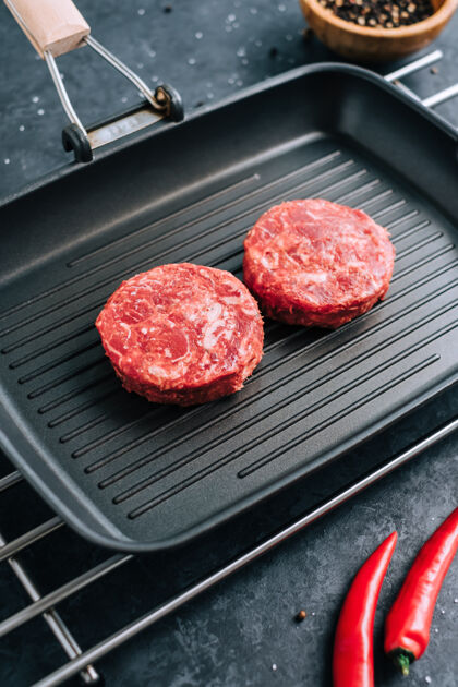 圆形新鲜的生牛肉碎放在黑烤盘上 配上红辣椒做汉堡烧烤餐厅排骨