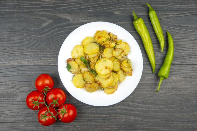 欧芹木桌上的白色盘子里放着香草和蔬菜的熟炸土豆有机素食烹饪