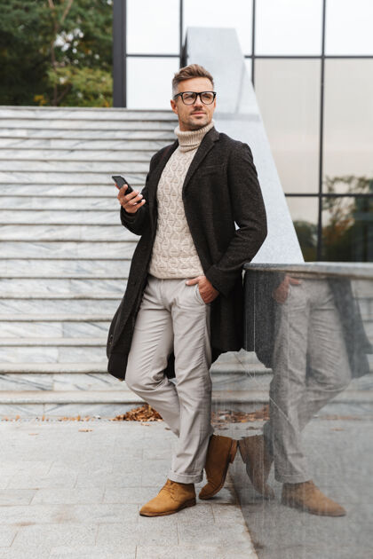 城市30多岁的成熟男人戴着眼镜 穿过城市街道 使用智能手机的画面胡须白种人成人