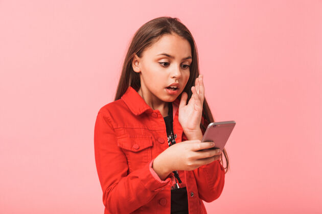 女人这张照片是一个穿着休闲装的少女站在红墙上 用智能手机拍摄的孩子站年轻