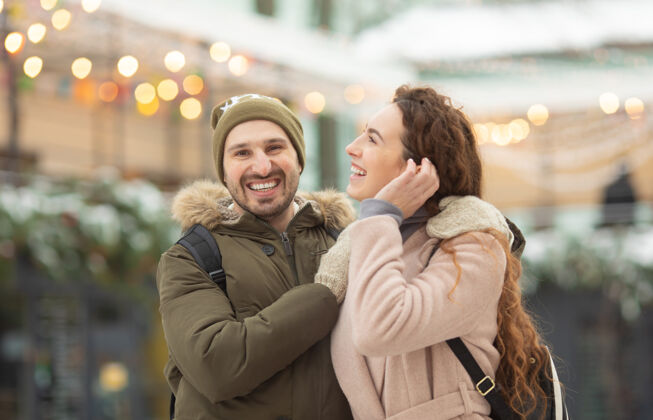 下雪在冬季公园里 拥抱着微笑着看着相机的情侣情感女孩候选人
