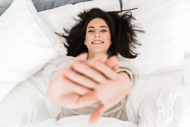 中年图为30多岁的黑发女子躺在家中的床上微笑成熟白种人舒适