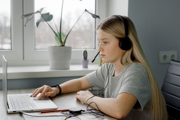 课程远程学习 戴着耳机的少女在家里上网络课在线设备计算机