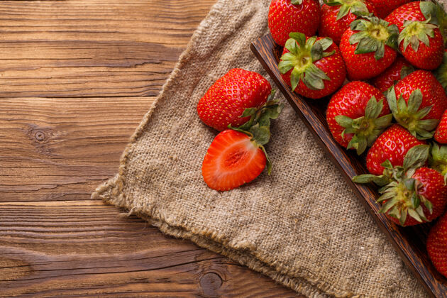 成熟的熟透的草莓放在亚麻布和桌子的木盘上食物草莓美食