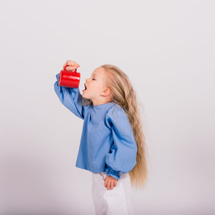 小微笑的小女孩抱着杯子 隔着白色背景.studio射击杯子女孩饮料
