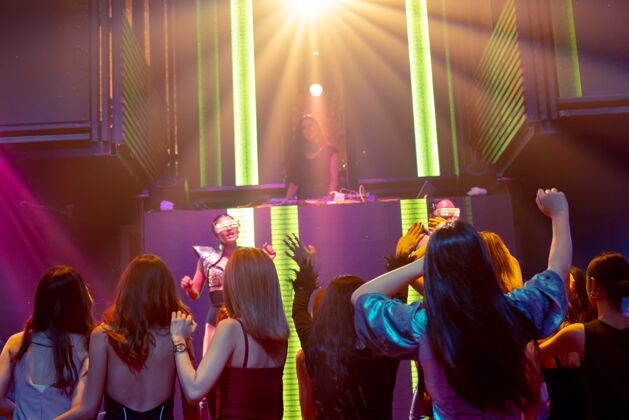 娱乐一群人随着舞台上dj的音乐节拍在迪斯科夜总会跳舞音乐会俱乐部生活方式