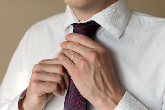 商务一个结了婚的男人手上戴着戒指 他就把领带弄直了假日婚礼优雅