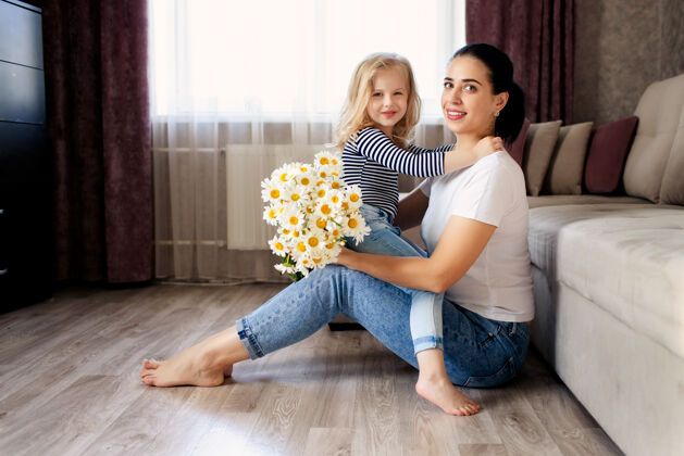 童年爱心妈妈和小女儿在家拿着一束鲜花雏菊一家人在一起玩得很开心生活方式女儿欢呼