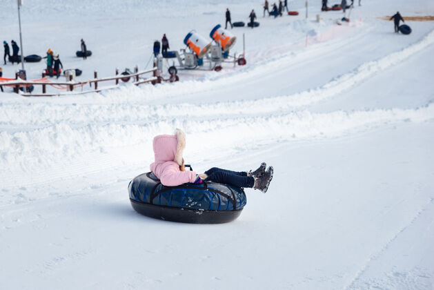 休息一个小女孩骑着管子滑下滑梯雪堆情绪冬天