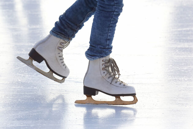 冻结溜冰场上穿着溜冰鞋的女人的腿娱乐训练冬季