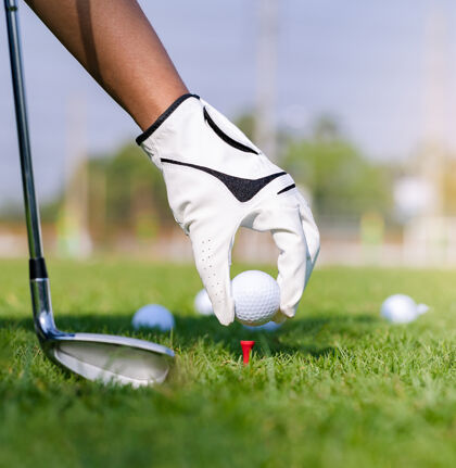 高尔夫球场手戴手套把高尔夫球放在球场的球座上高尔夫背景手套