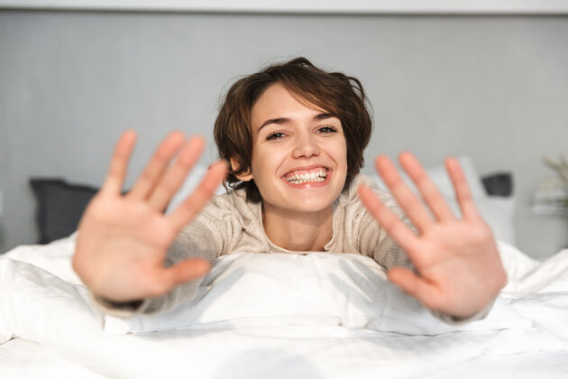 室内快乐的黑发女人在家躺在床上玩得很开心室内卧室吸引