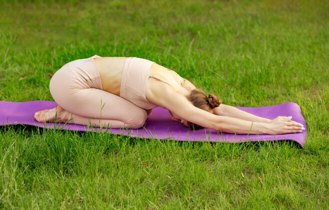 身体可爱的女运动员一边练习瑜伽一边在垫子上伸展身体女人平静锻炼