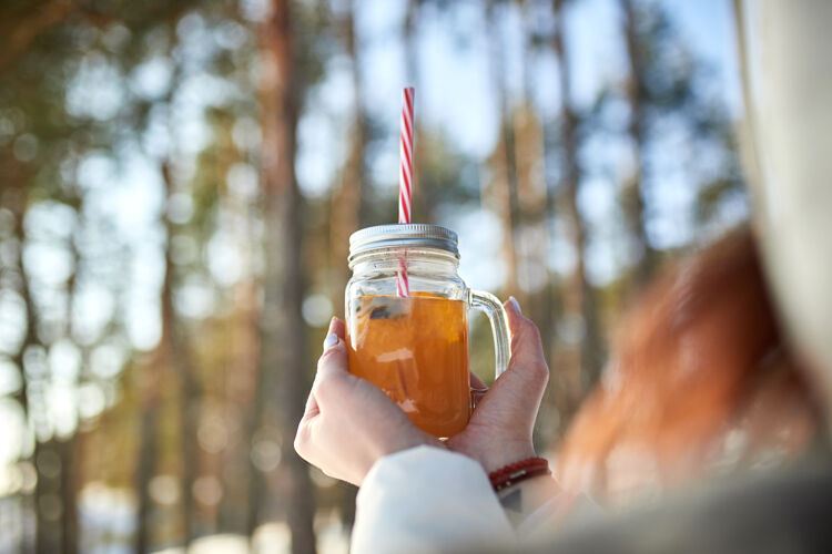 杯子冬天的森林里 女人的手拿着一杯熟酒季节酒精香料