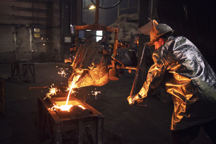 铸造穿着防护服和安全帽的铸造工人用热铁水填充模具 为工业制造零件铁安全工人