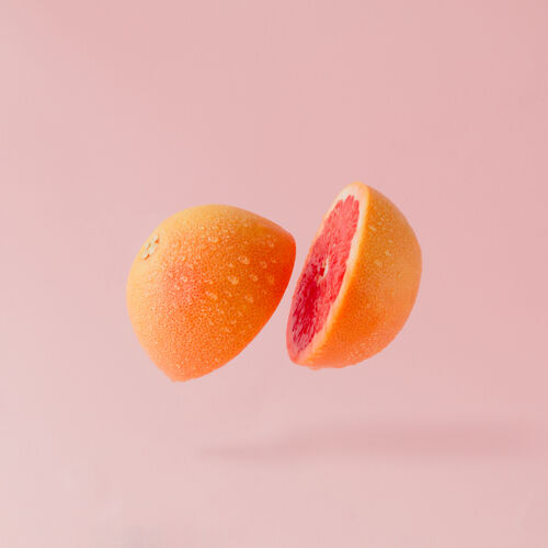 饮食葡萄柚片在淡粉色的表面抽象水果多汁