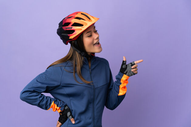 表情十几岁的骑自行车的女孩用手指着侧面展示产品手势健康骑行