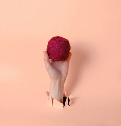 绞女性的手拿着线穿过撕裂的粉红色纸简约创新医学理念纸物体蓬松