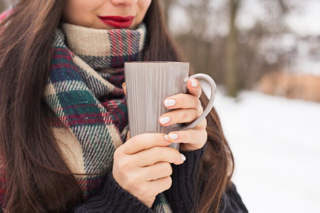 日出美丽快乐微笑的女人拿着一个杯子在冬天的大街上滑雪寒冷咖啡