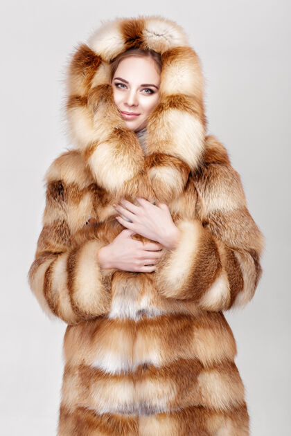 制造身着豪华狐皮的年轻金发美女肖像大衣.冬天灰色背景时尚可爱昂贵魅力
