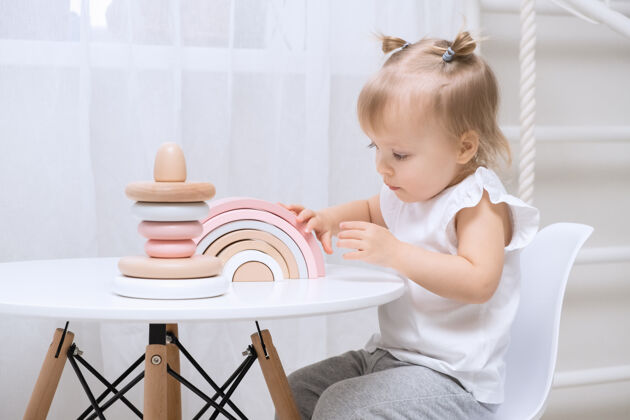 女孩小女孩在家里玩木制玩具小桌子可爱的女孩和天然玩具创意房间教育
