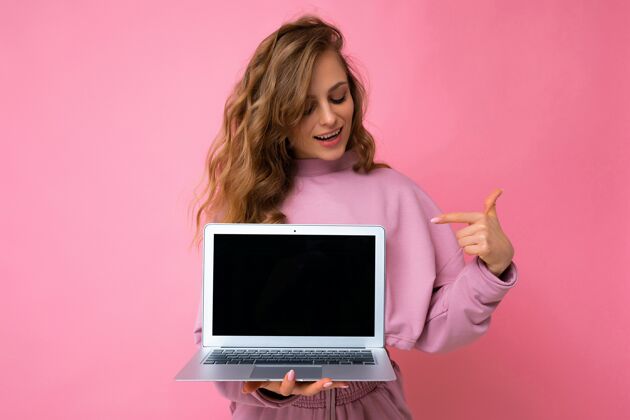 笔记本电脑美丽迷人的深金色卷曲的年轻性感的年轻女子在上网本键盘上看镜头电子屏幕计算机