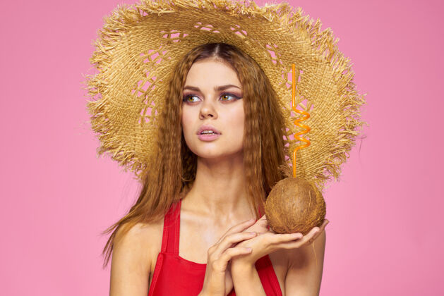 异国水果戴着草帽的椰子鸡尾酒的女人异国情调的度假夏日粉色的墙壁黑发身体模特