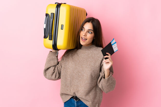 文件年轻的白人妇女带着手提箱和护照在度假时被隔离在粉色背景下旅李女孩