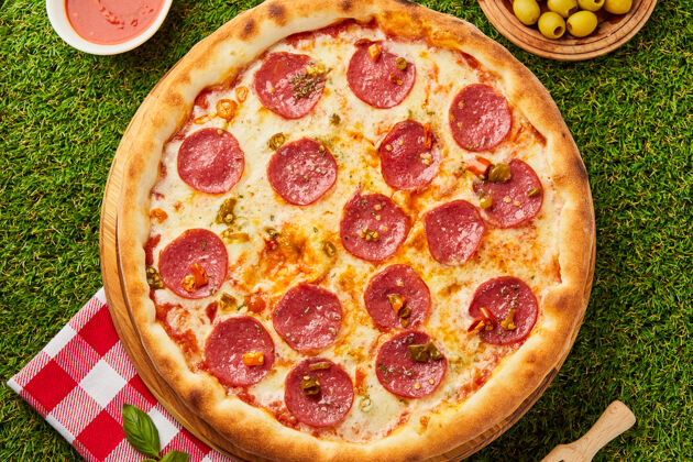 辛辣传统的意大利披萨 意大利香肠 意大利香肠 意大利马苏里拉和罗勒放在绿草上比萨店肉热的