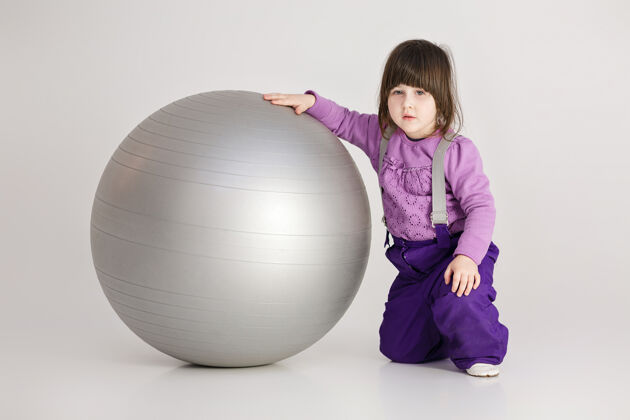 房子穿着紫色衣服的可爱小女孩 灰色背景上有一个健身用的大球脸无忧无虑可爱