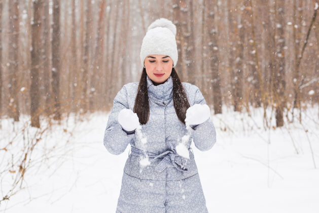 雪花冬季 节日和人们的理念-开朗的年轻女子快乐地漫步在冬日的森林里雪花微笑寒冷