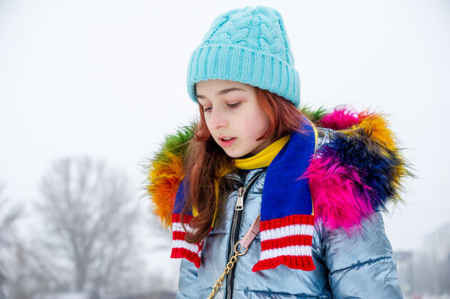 温暖穿着暖和衣服的年轻女孩的画像服装.青少年下雪天戴蓝帽子的女孩天气帽子女人