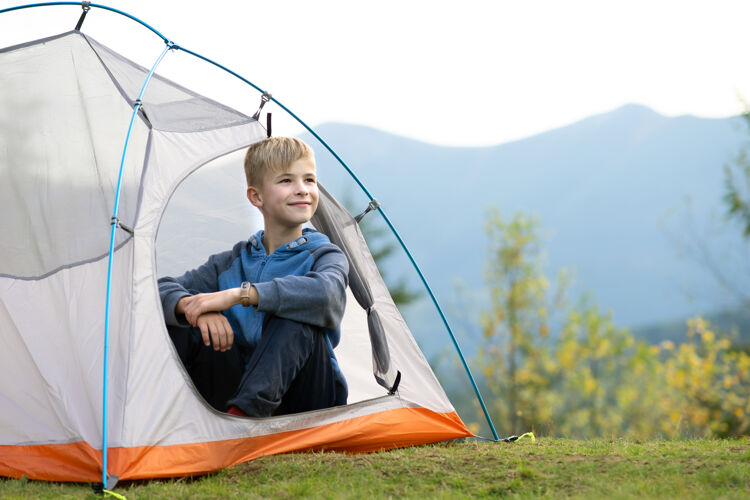 徒步旅行快乐的小男孩在山上露营地的旅游帐篷里休息 欣赏美丽的夏天大自然远足积极的生活方式理念宁静旅游山顶