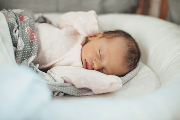 美丽一个正在睡觉的新生婴儿的特写照片 她穿着暖和的衣服 被子盖在床上女儿睡觉时间小
