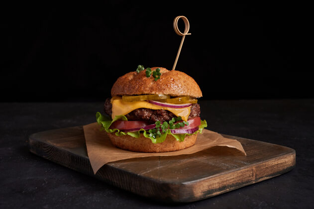 美味自制牛肉汉堡配奶酪 西红柿 红洋葱 黄瓜和生菜 黑石板背景 不健康食品 复制空间新鲜午餐叶子