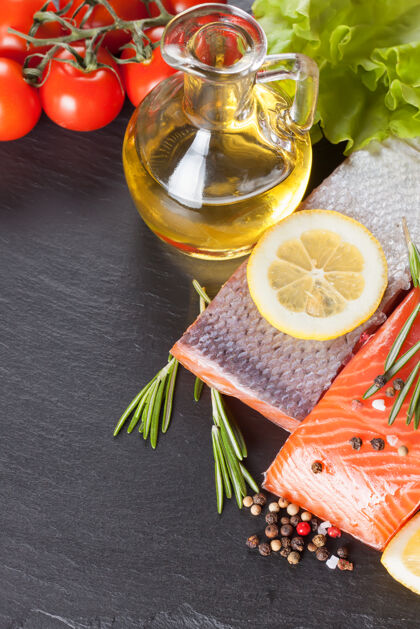 油把生三文鱼片 香料和蔬菜放在深色的石板桌上盐芳香牛排