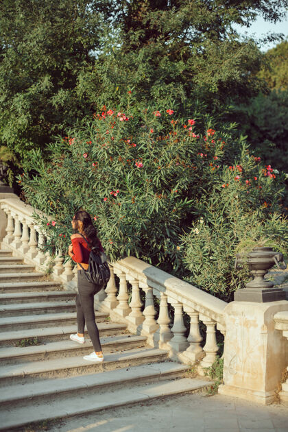地标背着背包的年轻女孩户外快乐穿着休闲服的女人在城市公园里散步著名年轻人楼梯