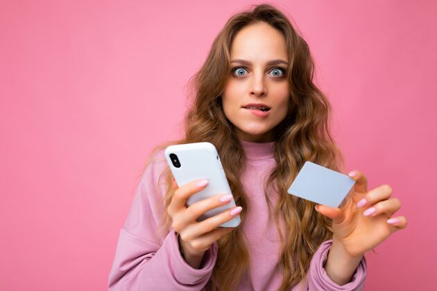 手机特写肖像照片相当震惊年轻的金发卷发女子穿着粉红色的衣服孤立了客户交易在线