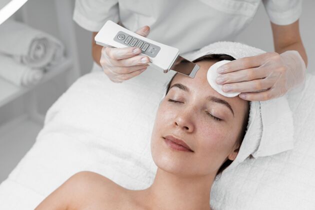 美容治疗美容师为女性客户做美容常规治疗面部护理美容治疗
